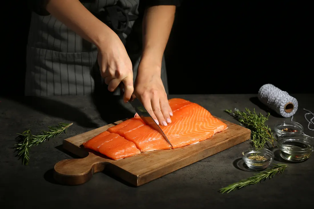 A fishmonger filleting fish on a board